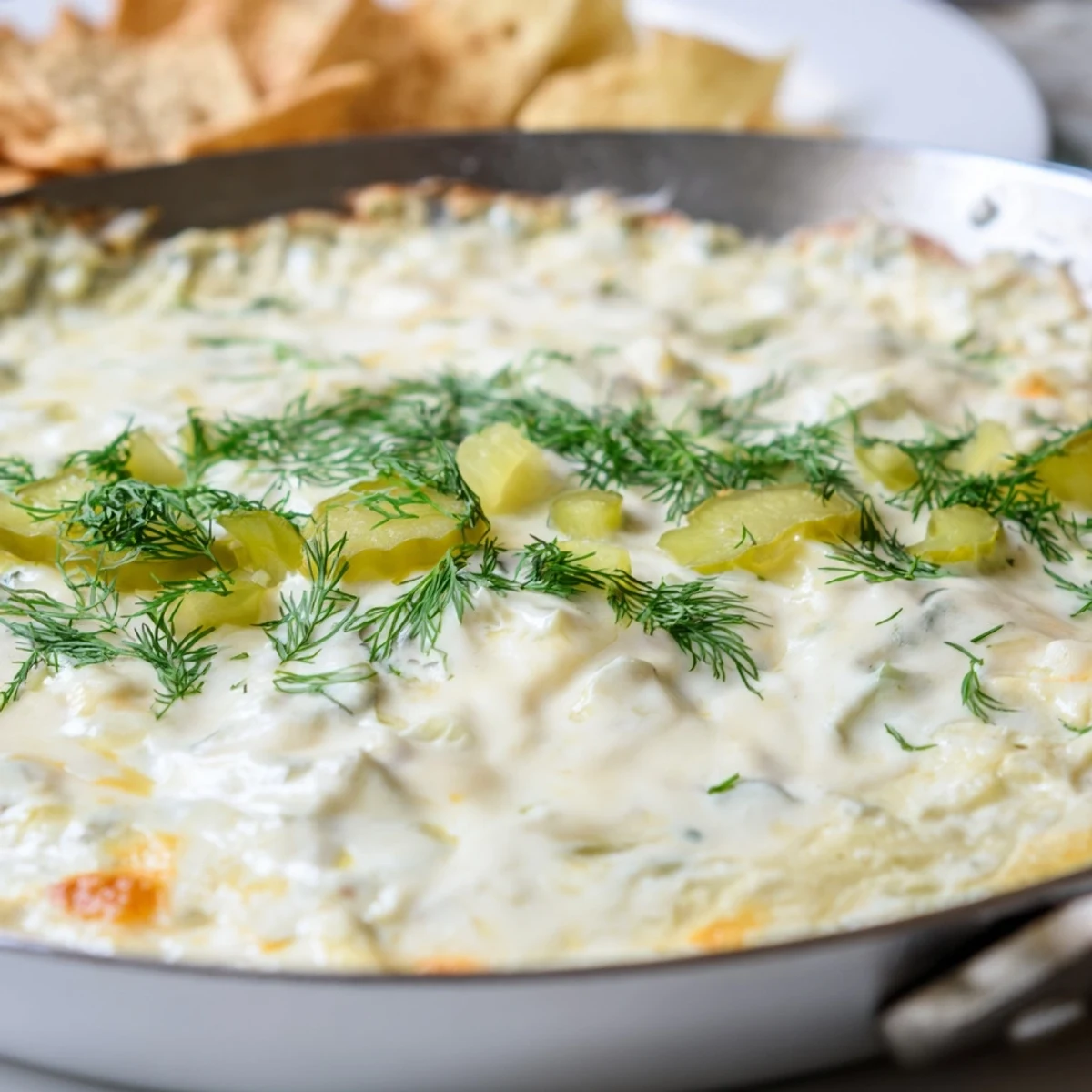 Creamy dill pickle queso fundido dip served bubbling hot with crunchy tortilla chips.  