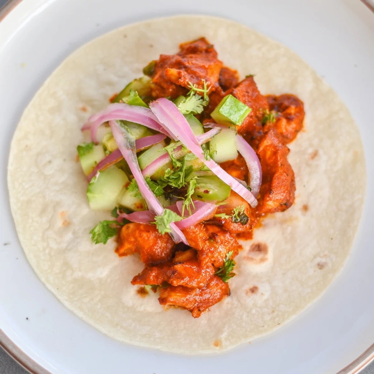 Close-up of sticky chicken tikka masala tacos, showing the flavorful sauce and toppings, inviting aroma.