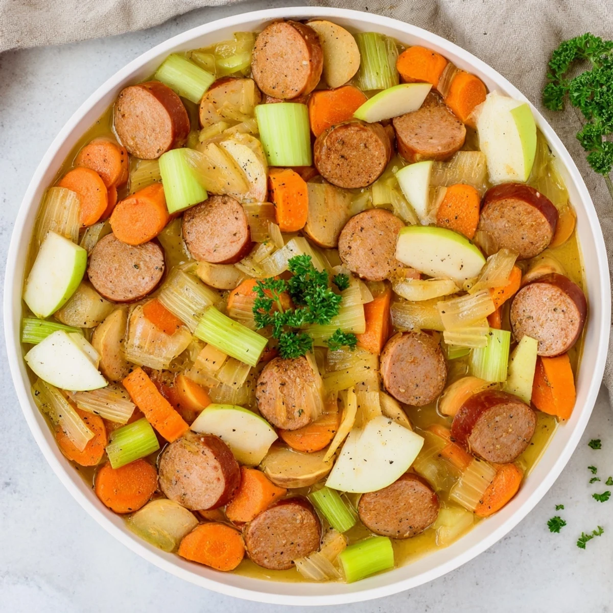 Steaming Stovetop Sausage, Celery, and Apple Hotpot with browned sausage pieces and tender vegetables.