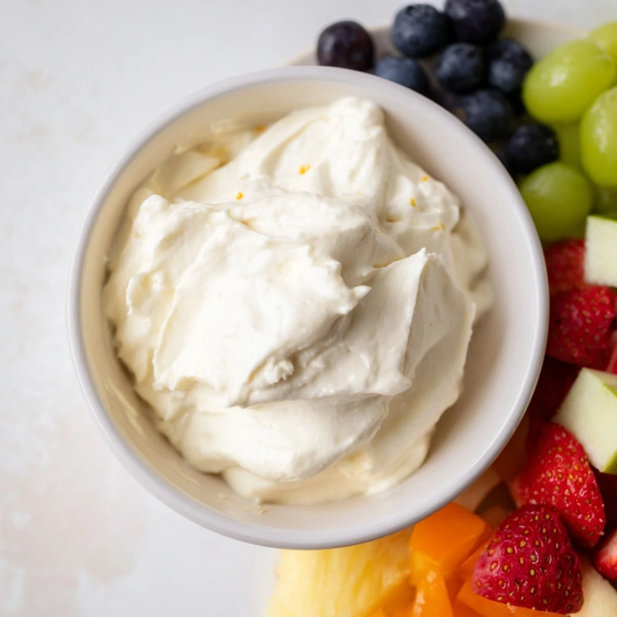Creamy cream cheese fruit dip in a bowl: a vibrant spread surrounded by colorful fresh fruit.