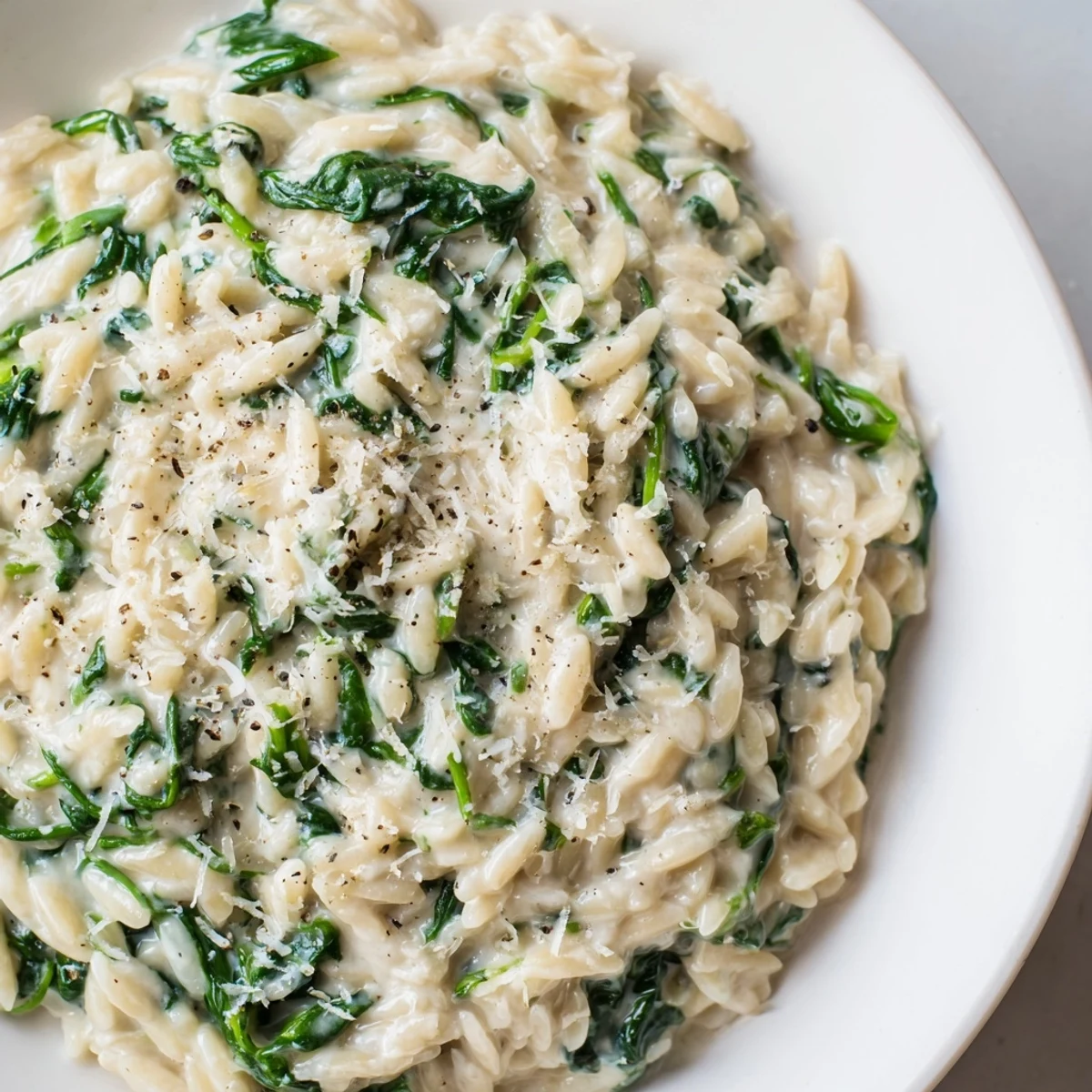 Creamy spinach orzo, a one-pan dish, served hot and topped with fresh Parmesan cheese.