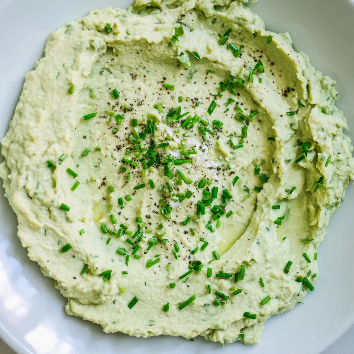Smooth Avocado Cottage Cheese Dip, speckled with chives, ready to be spread or enjoyed with crackers.