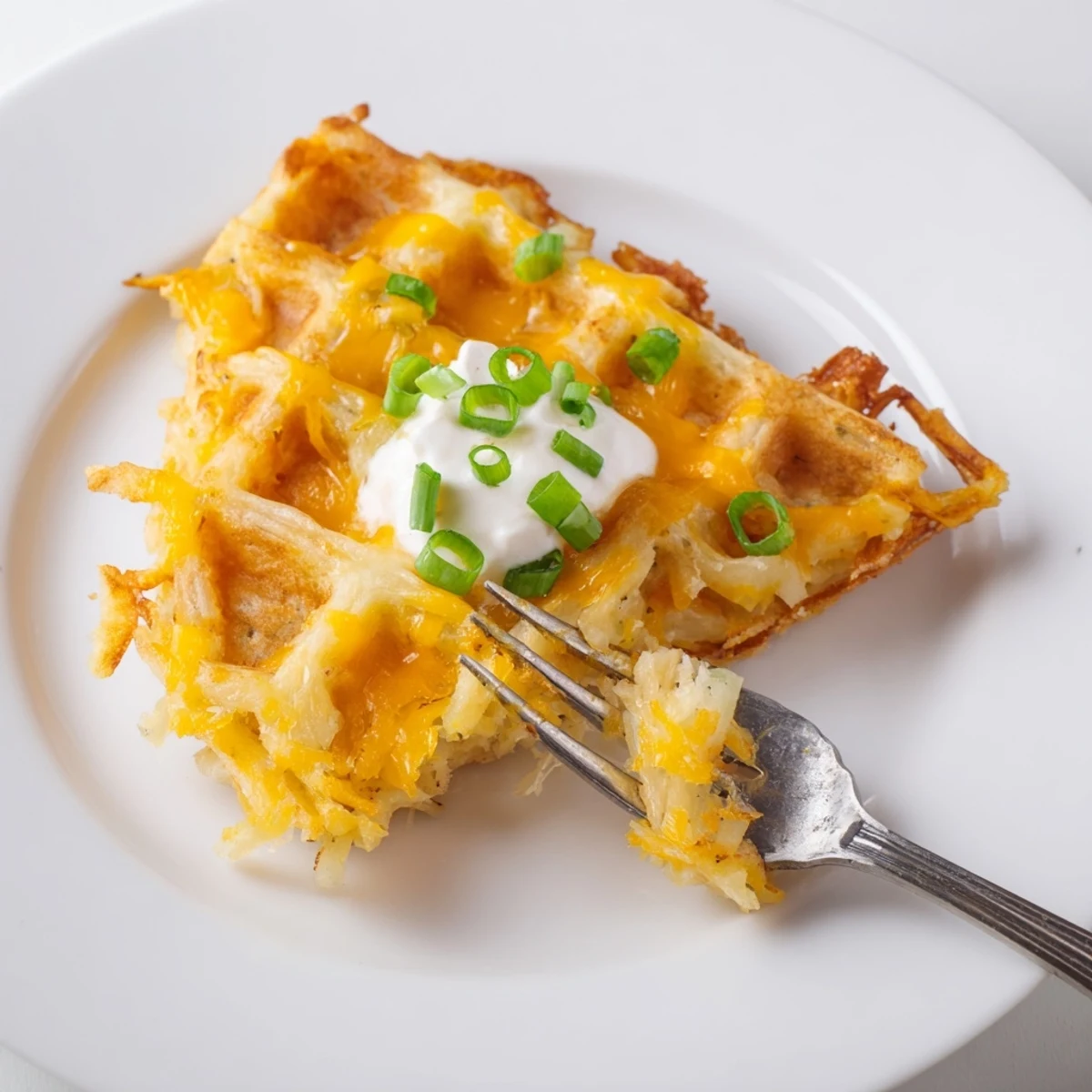 A steaming plate of cheesy hash brown waffles, perfect for a hearty brunch with melted cheese.