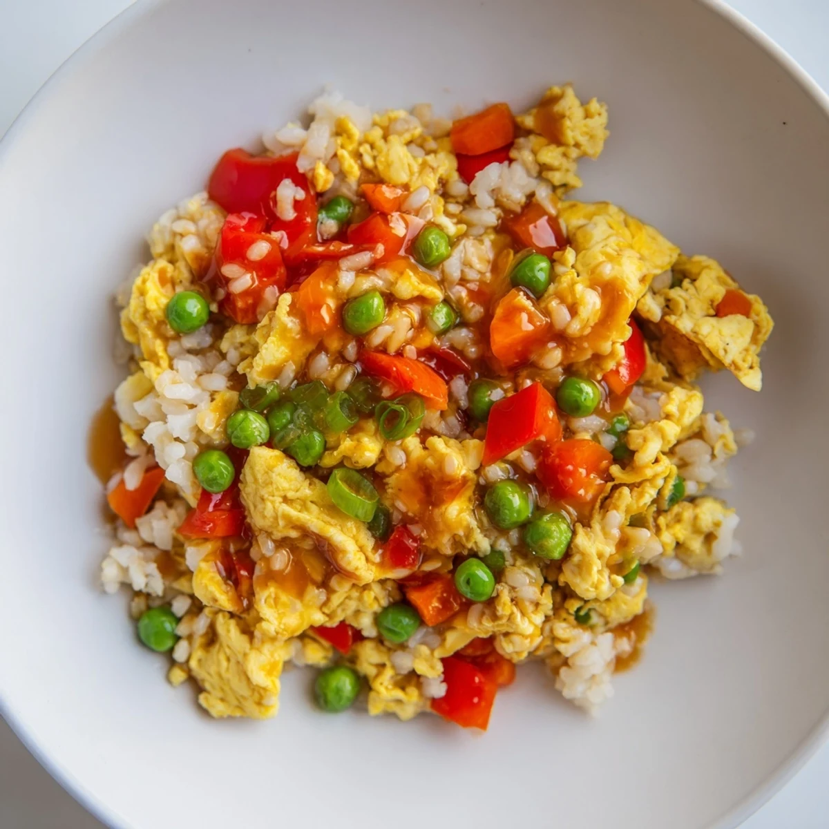 A steaming bowl of flavorful Egg Fried Rice, garnished with fresh scallions, is ready to serve.