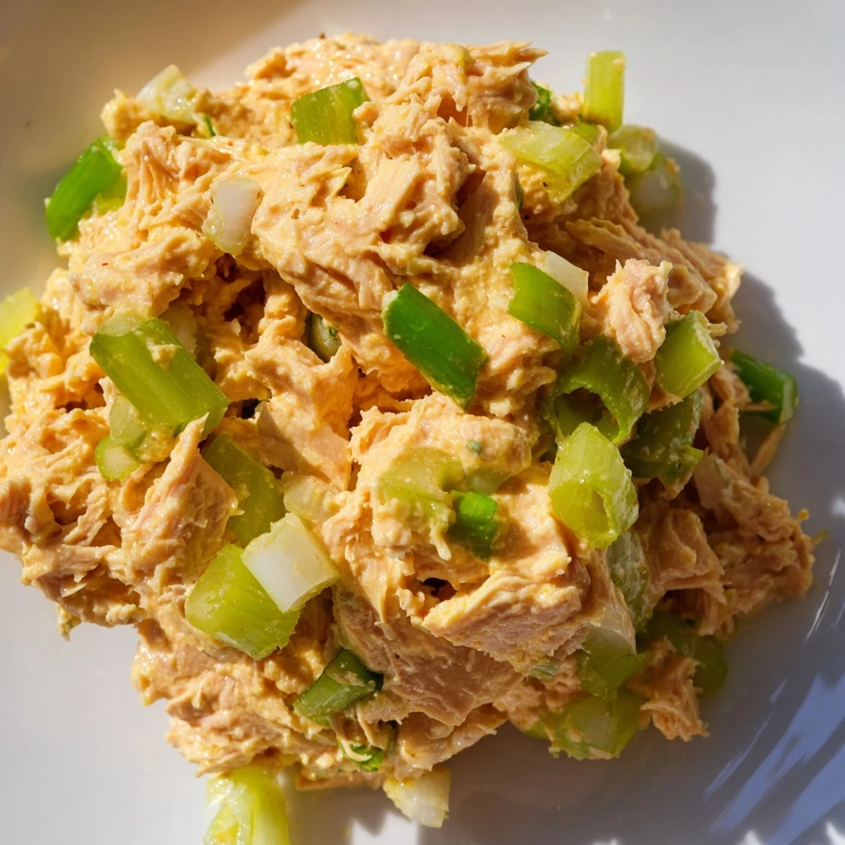 A serving of Spicy Zesty Tuna Salad in a lettuce cup, highlighting the light, low-carb presentation with a side of lemon wedges and a sprinkle of black pepper.