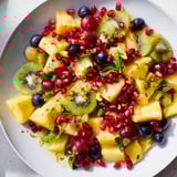A delicious Three Kings Royal Fruit Platter overflowing with juicy mangoes, grapes, and pomegranate seeds.