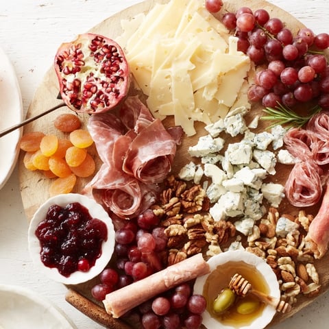 A Christmas 2025 festive grazing board overflowing with cheeses, meats, fruits, and crackers for the holidays.