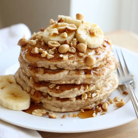 Stack of fluffy Peanut Butter Maple Oat Pancakes, enticing with warm butter and sliced bananas.