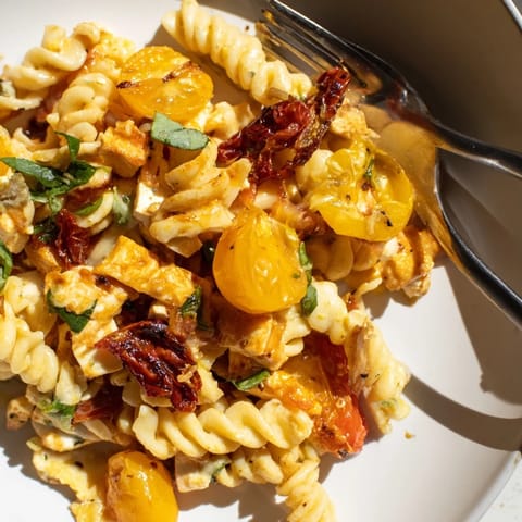 Baked feta pasta served warm, garnished with fresh basil and olive oil drizzle.  