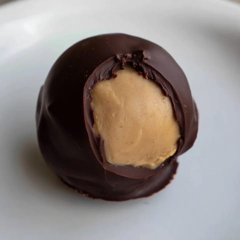 Golden-brown peanut butter buckeyes, a classic American treat, chilling after being dipped in chocolate.