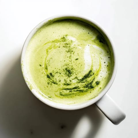 Warm, vibrant green Coconut Ginger Matcha Winter Immunity Latte, inviting with ginger and coconut aromas and frothy texture.