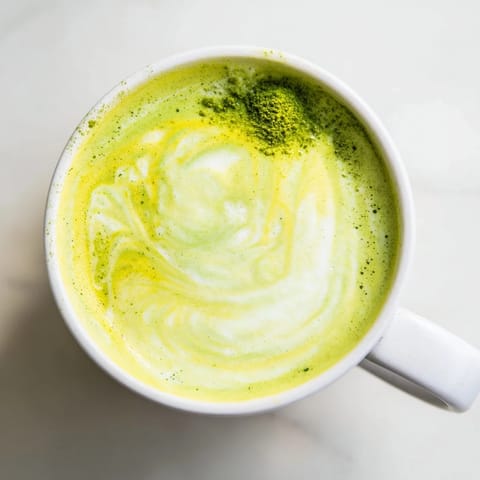 Steaming mug of Coconut Ginger Matcha Winter Immunity Latte, topped with frothy matcha, is perfect on a cold day.