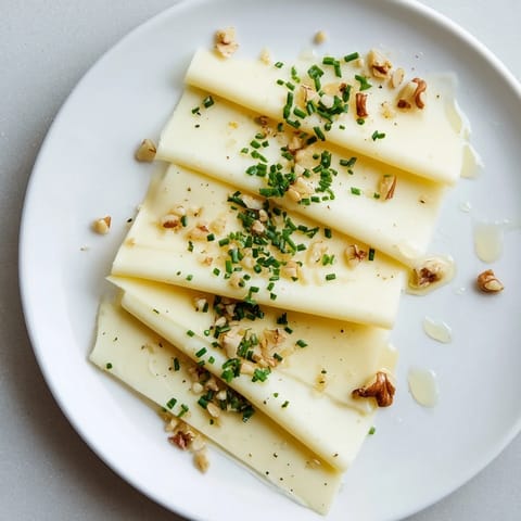 Freshly layered Swiss cheese fan, inviting and simple appetizer with optional walnut garnish and pepper.