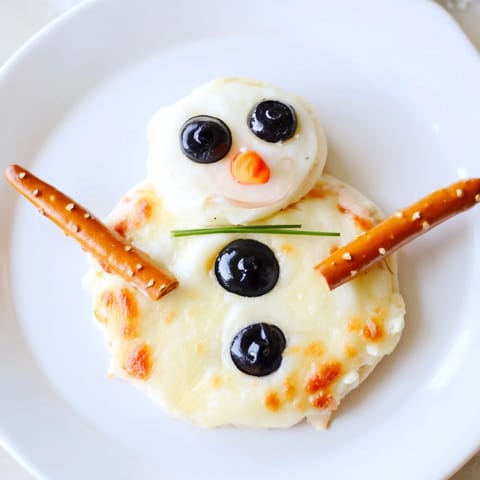 Adorable Melted Snowman Cheese Bites, featuring mozzarella faces, black olive eyes, and pretzel arms, ready to serve.