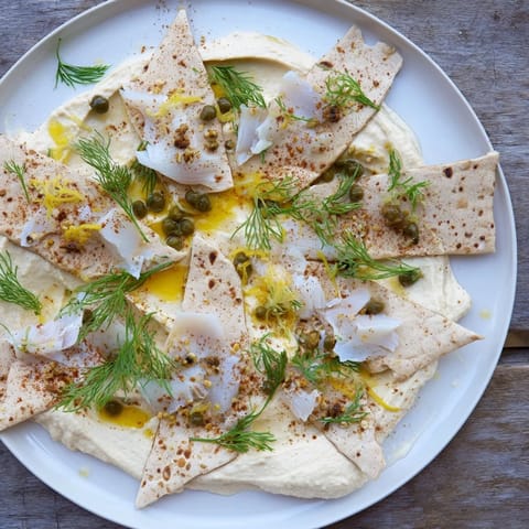 Delectable Driftwood Beach appetizer: fresh dill, smoked fish, and sesame seeds atop creamy hummus.