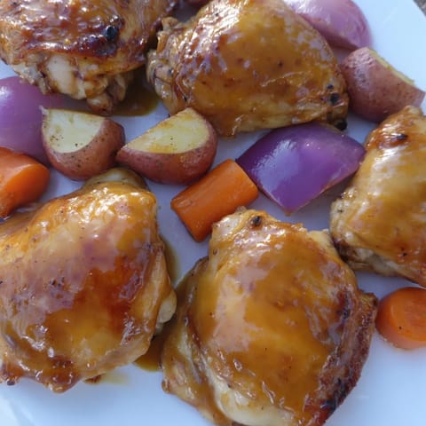 Sheet pan showcasing glistening Maple Dijon Chicken Thighs, perfectly roasted with tender carrots and potatoes.