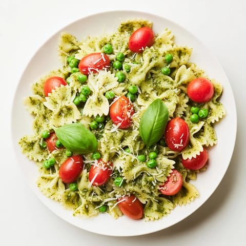 Green Pesto Pasta Salad tossed with fresh basil leaves and grated Parmesan, perfect for a refreshing lunch or potluck.  