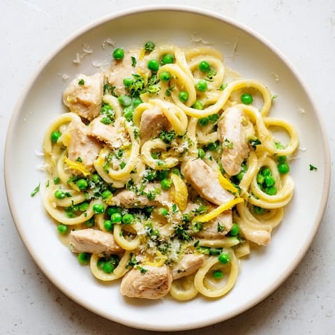 Family-style Garlic Butter Chicken & Pea Pasta served with fresh parsley and grated Parmesan cheese.