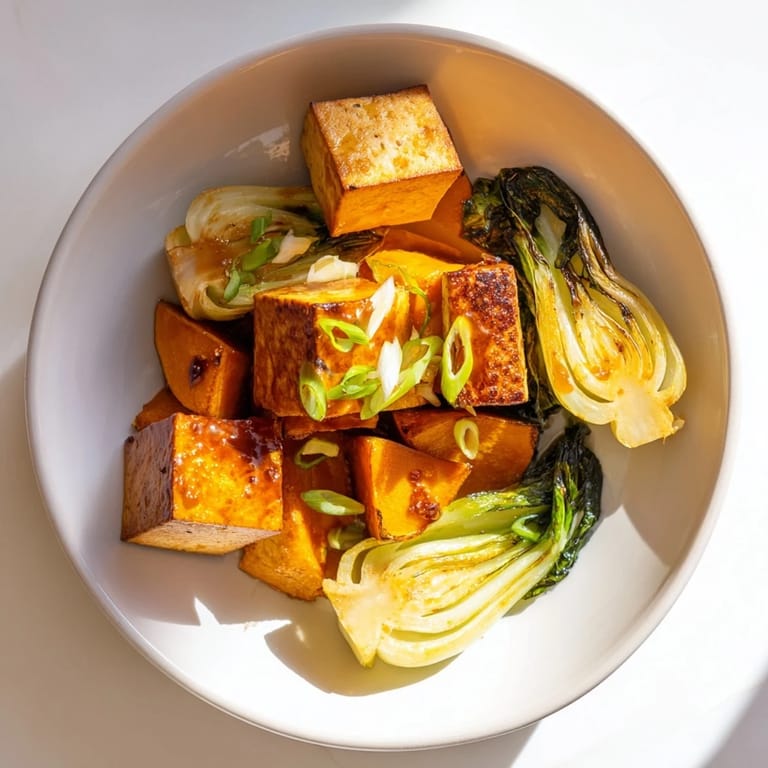 A close-up view of Miso-Glazed Tofu and squash, a flavorful dish garnished with scallions.
