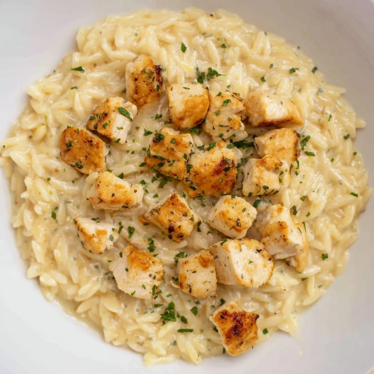 This One-Pot Cajun Chicken Alfredo Orzo features a vibrant swirl of parsley garnishing the dish.
