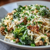 Creamy Garlic Turkey & Broccoli Orzo served warm in a skillet, garnished with fresh parsley and melted Parmesan.